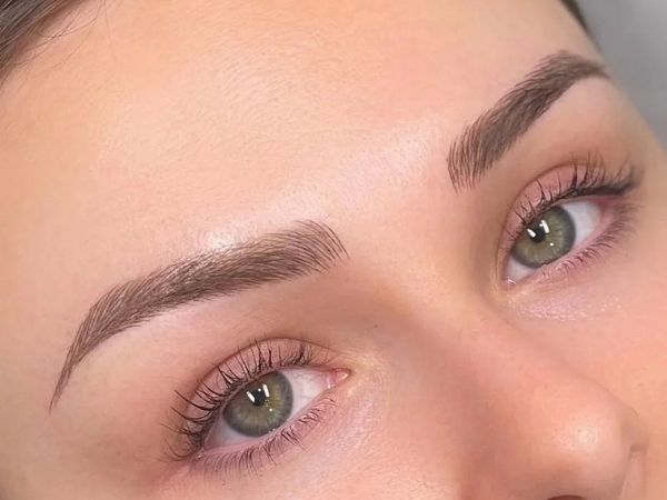 Close-up of eyebrow microblading semi permanent makeup treatment showing natural hair-like strokes on brows